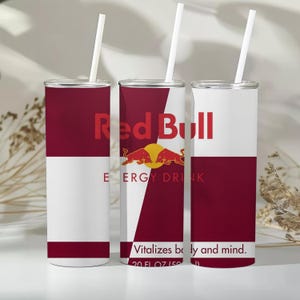 Könnte beinhalten: Drei zylindrische Trinkbecher mit einem Red Bull Energy-Drink-Design in Kastanienbraun und Weiß. Jeder Becher hat einen weißen Strohhalm, das Red Bull-Logo, den Text Energy Drink und den Satz Vitalizes body and mind. 591 ml ist aufgedruckt.