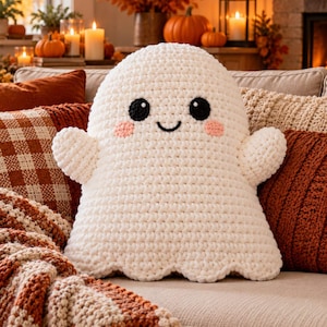 May include: A white crochet ghost plush toy with a rounded head, two small arms, and a scalloped bottom edge. The ghost features two round black eyes, a small black stitched smile, and two soft pink circular patches on its cheeks.