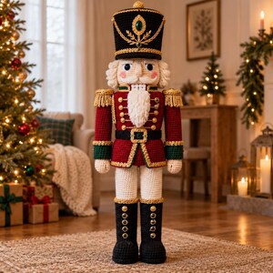 May include: A crocheted nutcracker figure featuring a tall black hat with gold trim and a green gem, a red jacket with gold buttons and fringe epaulets, a white beard, and black boots with gold buttons. The figure has a structured, upright stance.