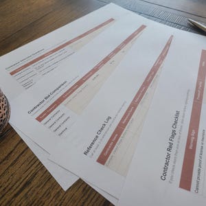 May include: A set of printed white paper documents featuring tables and text titled Contractor Interview Questions, Contractor Bid Comparison, Reference Check Log, and Contractor Red Flags Checklist, with a silver pen and a decorative glass object.