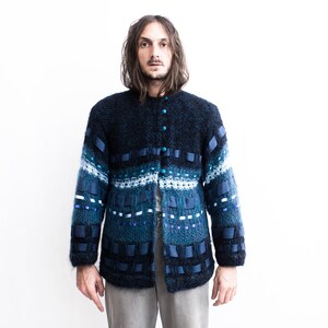 Peut inclure: Un cardigan en tricot bleu et noir avec un motif textur&eacute; et des accents de ruban bleu.