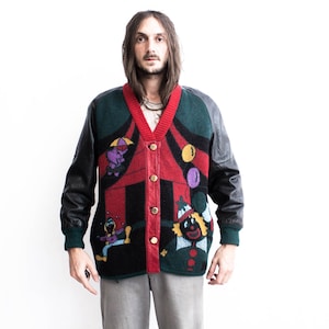 May include: A red, green, and black cardigan with a colorful circus theme. The cardigan has a v-neck and a button closure. The sleeves are black leather.