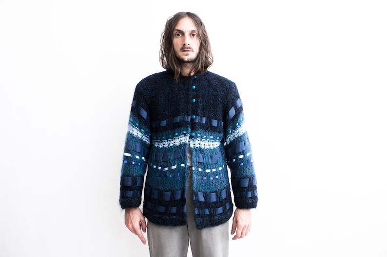Peut inclure: Un cardigan en tricot bleu et noir avec un motif textur&eacute; et des accents de ruban bleu.