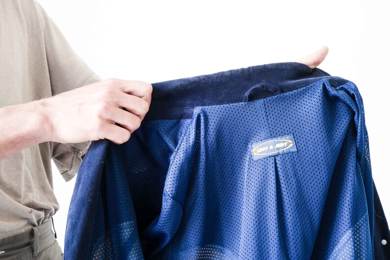Puede incluir: Una chaqueta azul con forro de malla y una etiqueta amarilla y azul que dice "ONO & JODY".