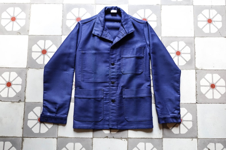 May include: A dark blue work jacket with a button-up front, two large pockets on the bottom, and a smaller pocket on the chest.