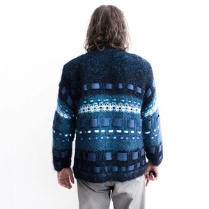 Peut inclure: Un pull en tricot bleu et noir avec un motif compos&eacute; de rayures bleues et blanches et de carr&eacute;s bleus.