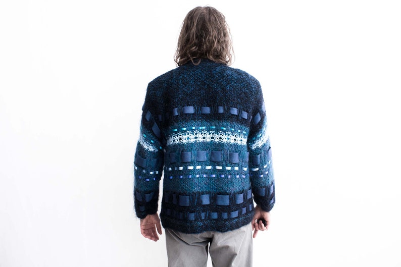 Peut inclure: Un pull en tricot bleu et noir avec un motif compos&eacute; de rayures bleues et blanches et de carr&eacute;s bleus.