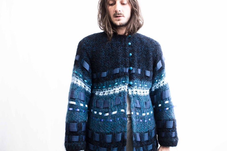 Peut inclure: Un cardigan en tricot bleu et noir avec un design unique comprenant des accents de ruban bleu et des boutons. Le cardigan a un tricot textur&eacute; et une coupe d&eacute;contract&eacute;e.