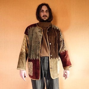 May include: A brown, green, and red patchwork jacket with a brown turtleneck sweater underneath. The jacket has a zipper closure and a quilted design.