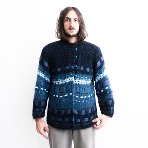 Peut inclure: Un cardigan bleu et noir &agrave; motifs avec une fermeture boutonn&eacute;e. Le cardigan est en tricot textur&eacute; et est d&eacute;cor&eacute; de rubans bleus et blancs.