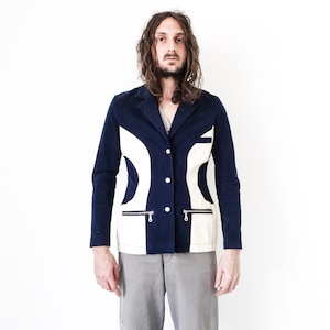 Puede incluir: Una chaqueta azul marino con un dise&ntilde;o geom&eacute;trico blanco y bolsillos con cremallera. La chaqueta tiene cierre de bot&oacute;n.
