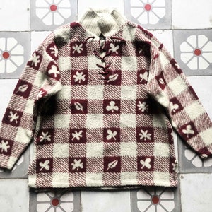 May include: A cream and burgundy checkered sweater with a lace-up neckline and a pattern of leaves and clover.