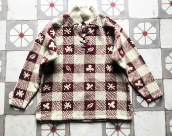 May include: A cream and burgundy checkered sweater with a lace-up neckline and a pattern of leaves and clover.