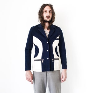 Puede incluir: Una chaqueta azul marino con dise&ntilde;os geom&eacute;tricos blancos. La chaqueta tiene cierre de bot&oacute;n y dos bolsillos con cremallera.
