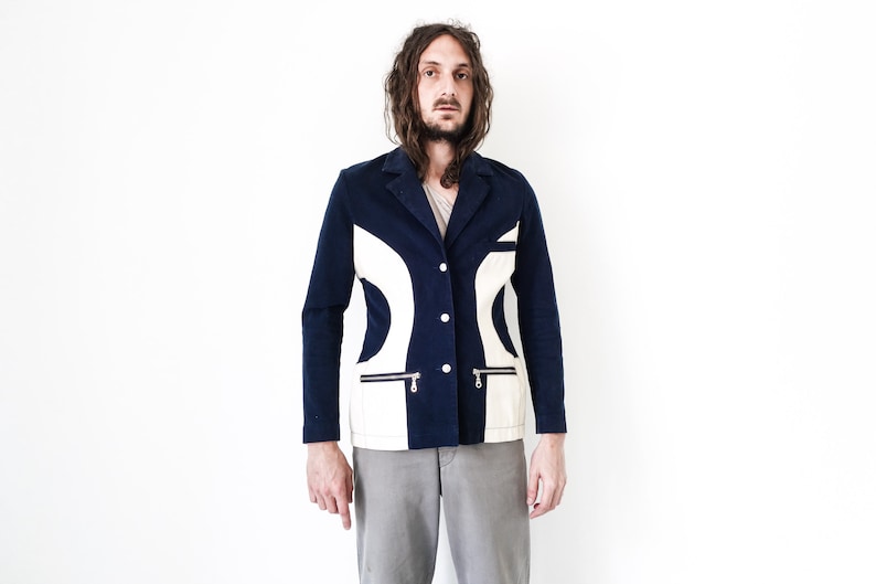 Puede incluir: Una chaqueta azul marino con dise&ntilde;os geom&eacute;tricos blancos. La chaqueta tiene cierre de bot&oacute;n y dos bolsillos con cremallera.