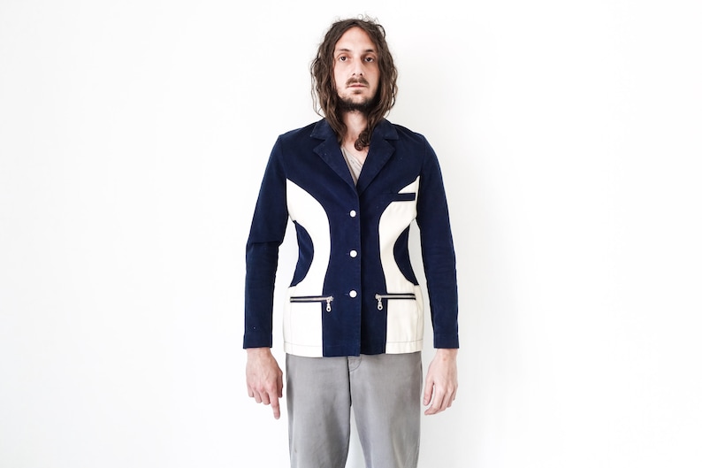 Puede incluir: Una chaqueta azul marino con paneles geom&eacute;tricos blancos y bolsillos con cremallera. La chaqueta tiene cierre de bot&oacute;n.