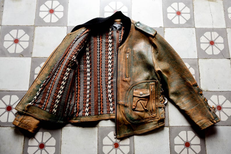 May include: A brown leather jacket with a patterned lining. The jacket has a zip fastening and multiple pockets.