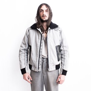 K&ouml;nnte beinhalten: Eine graue Bomberjacke mit schwarzem Besatz und Rei&szlig;verschluss. Die Jacke hat einen Kunstfellkragen und zwei Rei&szlig;verschlusstaschen.
