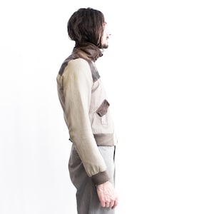 May include: A beige and brown bomber jacket with a zipper closure and a ribbed collar.