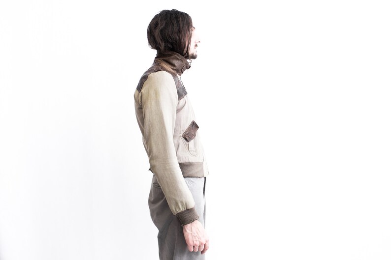 May include: A beige and brown bomber jacket with a zipper closure and a ribbed collar.