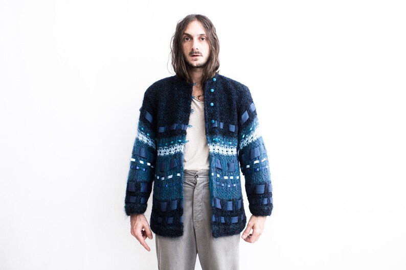 Peut inclure: Un cardigan bleu et noir &agrave; motifs avec un sous-pull blanc et un pantalon gris.