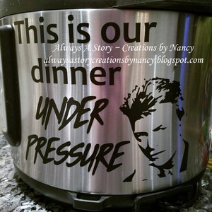 May include: A stainless steel Instant Pot with a black decal that reads "This is our dinner under pressure" and a silhouette of a person's face. The text "Always A Story - Creations by Nancy alwaysastorycreationsbynancyblogspot.com" is also on the decal.