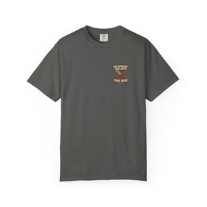 May include: A charcoal gray short-sleeve t-shirt featuring a small graphic on the left chest. The design includes a red circular gear icon with a wrench and the text "YOU WOULDN'T BELIEVE THIS SHIFT WAS". The shirt has a crew neckline and a standard fit.