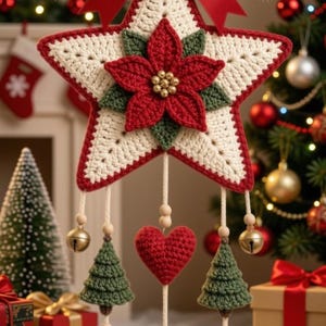 Peut inclure: Une décoration en forme d'étoile crochetée couleur crème avec une bordure rouge, surmontée d'un nœud en satin rouge, de branches de pin vertes et de baies rouges. Un poinsettia rouge est au centre. Trois cordons portent deux sapins verts.