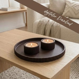 May include: A dark brown circular tray with a ribbed edge holding two matching dark brown ribbed candle holders, each containing a lit white candle. The image includes the text digitaler Download in a script font across the top.