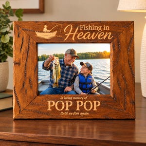 May include: A rectangular wooden picture frame with a dark brown, textured finish. The top is engraved with a fishing boat icon and the text "Fishing in Heaven." The bottom is engraved with "In loving memory of POP POP Until we fish again."