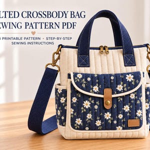 May include: A quilted crossbody bag sewing pattern PDF featuring text that reads QUILTED CROSSBODY BAG SEWING PATTERN PDF A4 PRINTABLE PATTERN STEP-BY-STEP SEWING INSTRUCTIONS. The bag is cream and navy blue with a daisy floral print.
