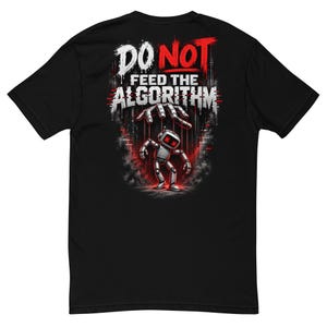 May include: A black short-sleeve t-shirt featuring a graphic print on the back. The design shows a robotic figure being controlled by strings from a hand above, with the text DO NOT FEED THE ALGORITHM in white and red distressed lettering.