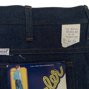 以下が含まれることがあります： Wranglerのラベルと「Lot 9250EN Regular 14 oz 100% Cotton 40 32」と書かれたタグが付いた、青いデニムのジーンズです。