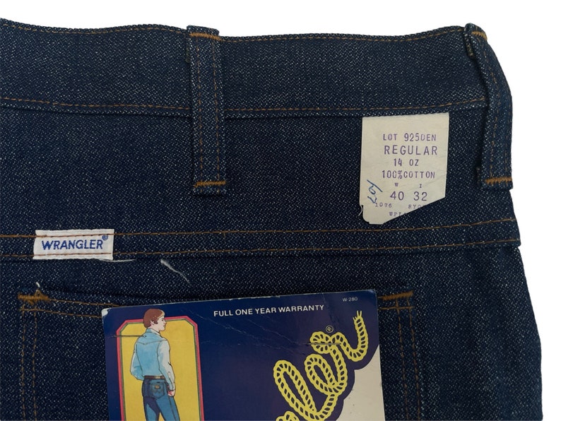 以下が含まれることがあります： Wranglerのラベルと「Lot 9250EN Regular 14 oz 100% Cotton 40 32」と書かれたタグが付いた、青いデニムのジーンズです。