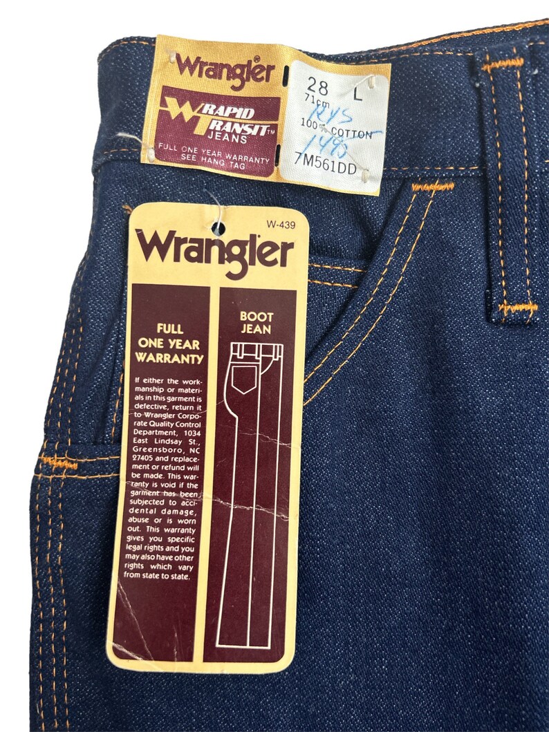 May include: A blue denim Wrangler bootcut jean with a brown label that says "Full One Year Warranty" and "Boot Jean". The label also includes the Wrangler logo and the text "W-439".