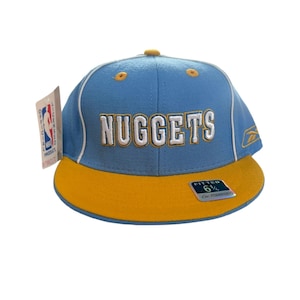 May include: A blue and yellow baseball cap with the word "Nuggets" embroidered on the front. The cap is a fitted size 6 1/2.