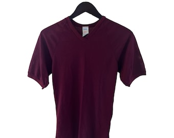May include: A maroon v-neck t-shirt with short sleeves. The shirt is hanging on a black hanger.