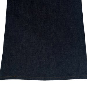 以下が含まれることがあります： 濃い青色のデニムジーンズの裾のクローズアップ。裾は茶色の糸で縫われています。