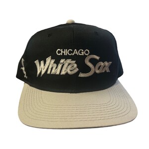 Może przedstawiać: Czarna i szara czapka bejsbolówka z haftowanym białym napisem "CHICAGO White Sox" z przodu.