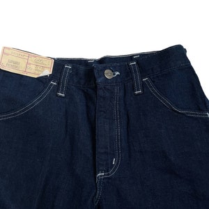 以下が含まれることがあります： 白いステッチと「3004PH-F CARPENTER PANTS 21"x30" MADE IN HONG KONG」と書かれた小さな紙タグが付いた濃い青色のデニムのカーペンターパンツ。
