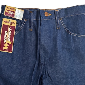 May include: A pair of blue denim jeans with orange stitching. The jeans have a label that says "Wrangler Rapid Transit" and a size tag that says "28" and "L".