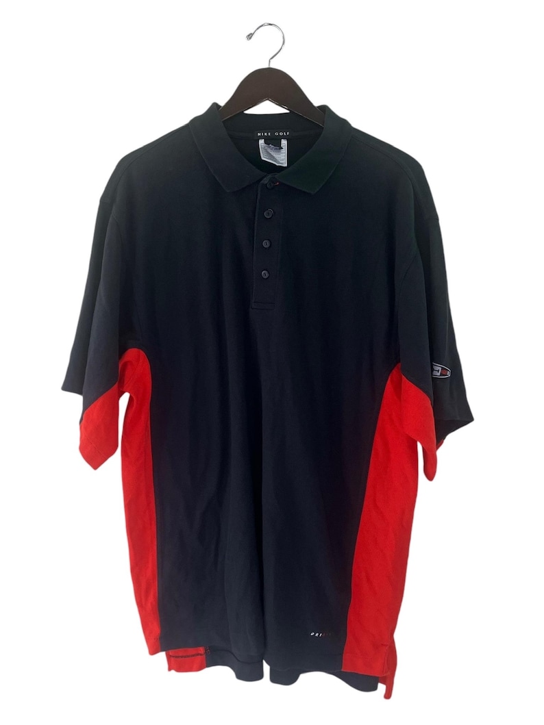 K&ouml;nnte beinhalten: Ein kurz&auml;rmeliges Poloshirt in Schwarz und Rot mit dem Schriftzug "Nike Golf" am Kragen.