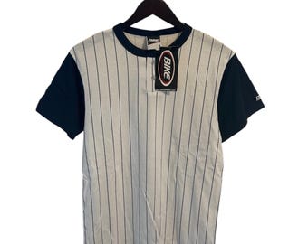 May include: A white and blue striped short-sleeved shirt with a navy blue collar and sleeves. The shirt has a button-up placket and a small tag that says "Bike" on it.