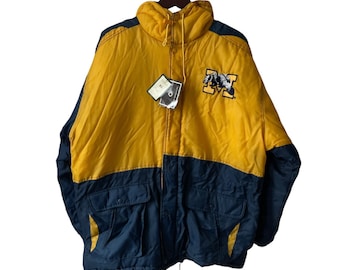May include: A yellow and blue reversible puffer jacket with a large embroidered "M" on the front. The jacket has a zipper closure and a drawstring hood.