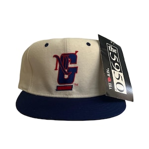 May include: A white and blue baseball cap with a red and blue embroidered logo that says "NG" on the front. The cap has a blue brim and a tag that says "the 5950 by NEW ERA".