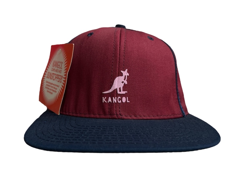 May include: A red and black baseball cap with a pink kangaroo logo and the word "Kangol" in white lettering.
