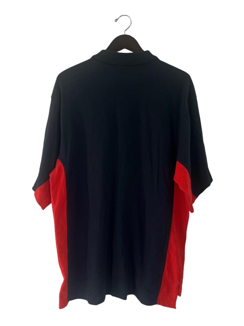 K&ouml;nnte beinhalten: Ein marineblaues Poloshirt mit roten Seitenteilen. Das Shirt hat kurze &Auml;rmel und einen Kragen.