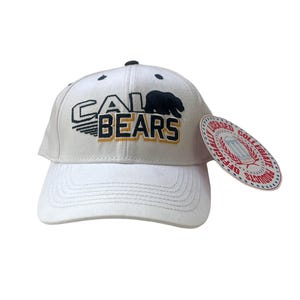 May include: White baseball cap with a black and gold embroidered logo that says "CAL BEARS" with a black bear silhouette. The cap has a curved brim and a tag that says "Officially Licensed Collegiate Products".