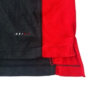 K&ouml;nnte beinhalten: Schwarz-rotes Sport-Shirt mit Dri-FIT-Logo. Das Shirt hat eine schwarze Seitenpartie und eine rote Seitenpartie.