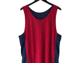 May include: A reversible vest top, red on one side and navy blue on the other, hangs from a wooden hanger. The sleeveless top features a scoop neck and a mesh-like texture on the red side, suitable for sports or casual wear.